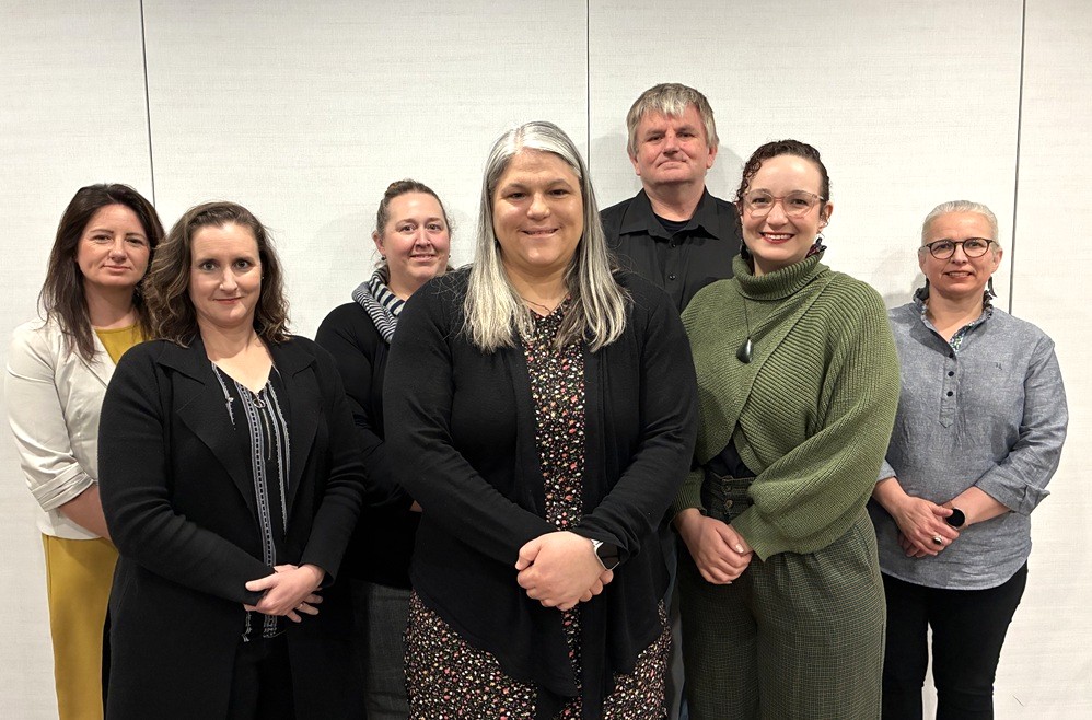 Seven members of the NZSL Board stand in a row and smile at the camera